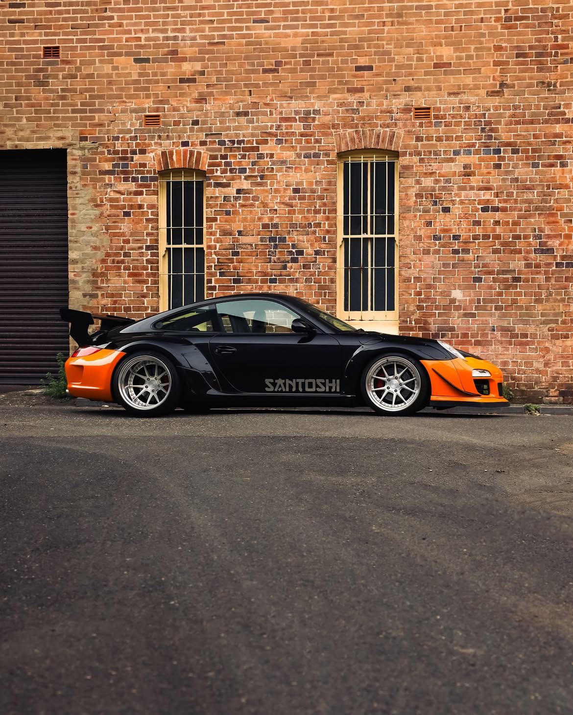 Black RWB widebody Porsche 911 with orange vinyl bumpers, by Roadbloc