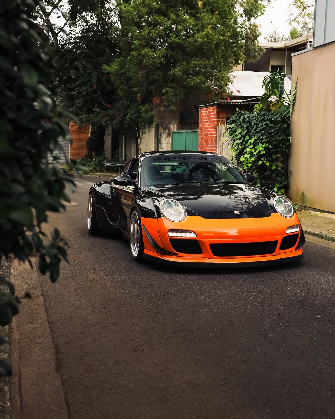 Black and orange RWB Kremer Porsche 911 RSR head on in a back lane, protected in paint protection film by Roadbloc