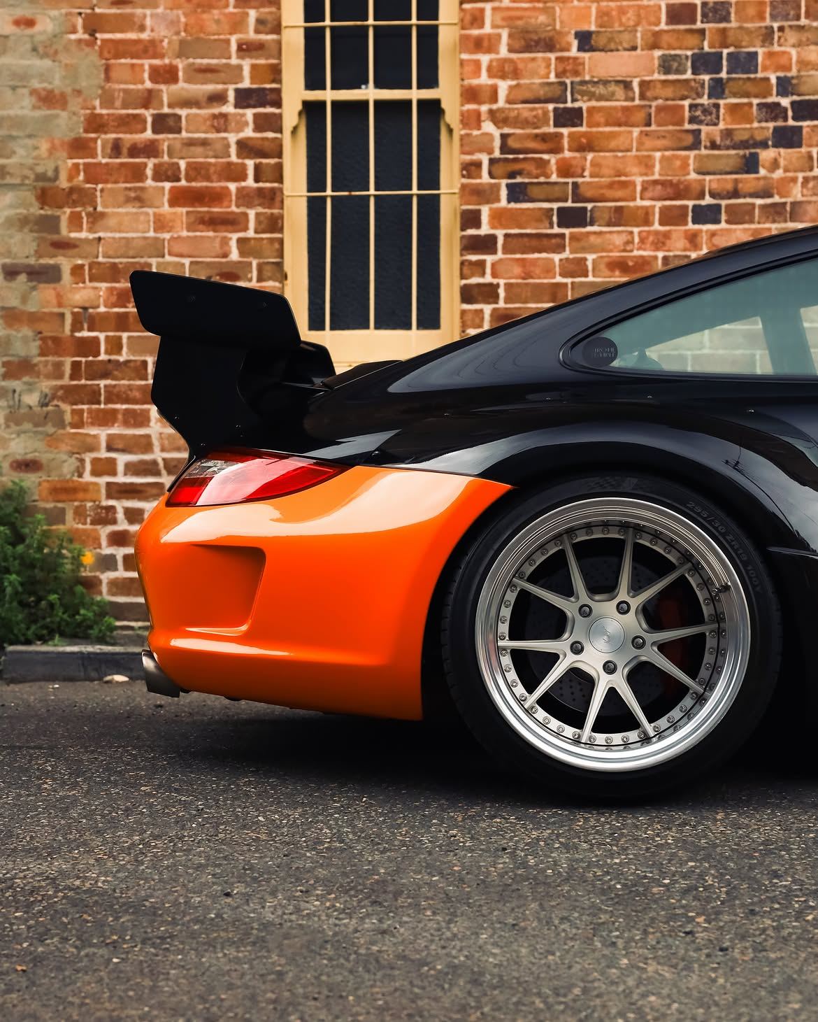 Black RWB widebody Porsche 911 with orange vinyl bumpers, by Roadbloc