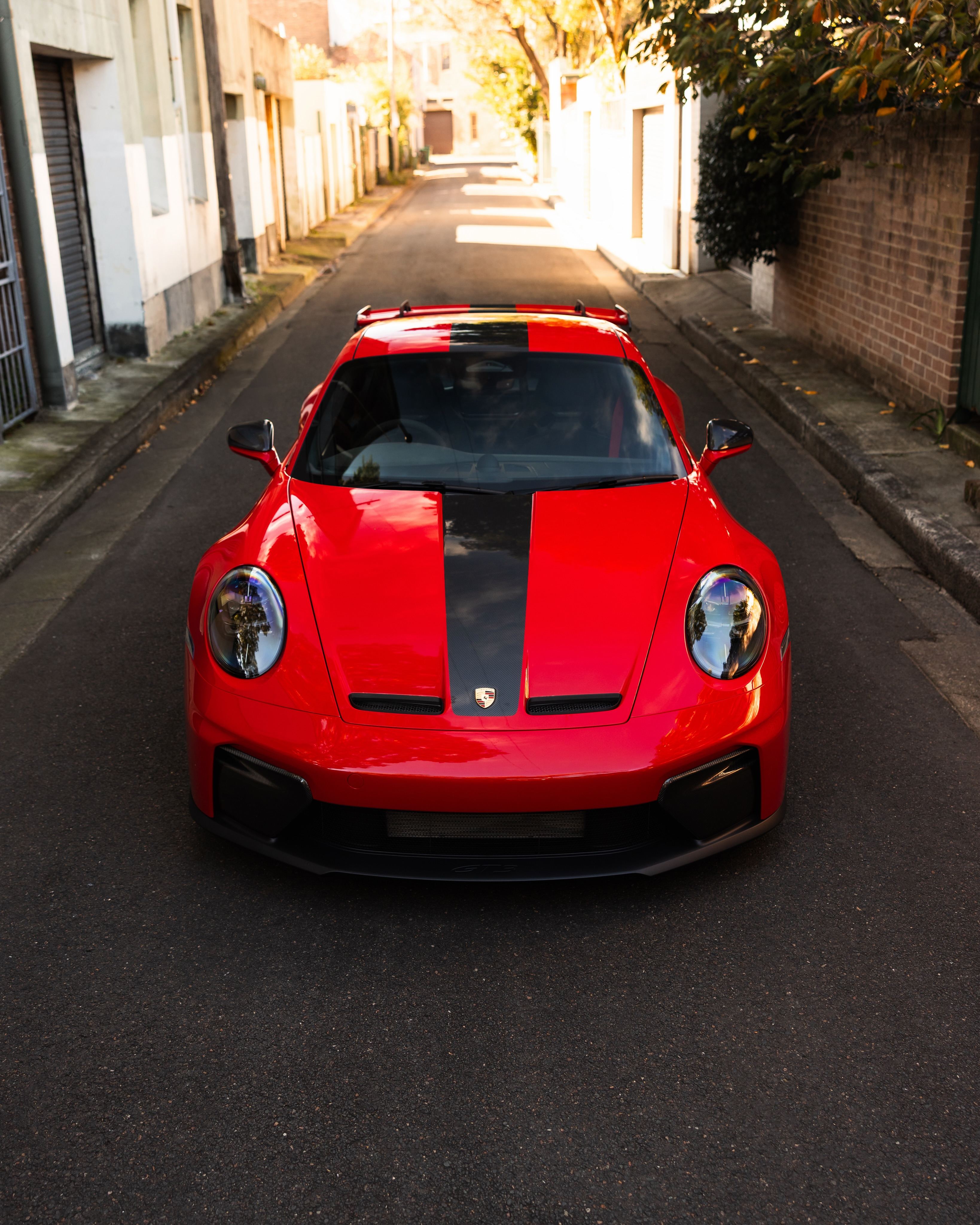 Red Porsche 911 GT3 head on in a narrow lane
