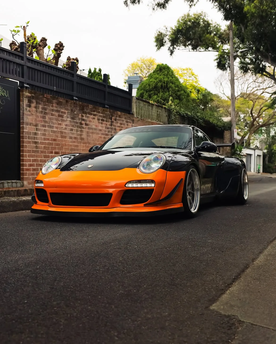 Black RWB widebody Porsche 911 with orange vinyl bumpers, by Roadbloc