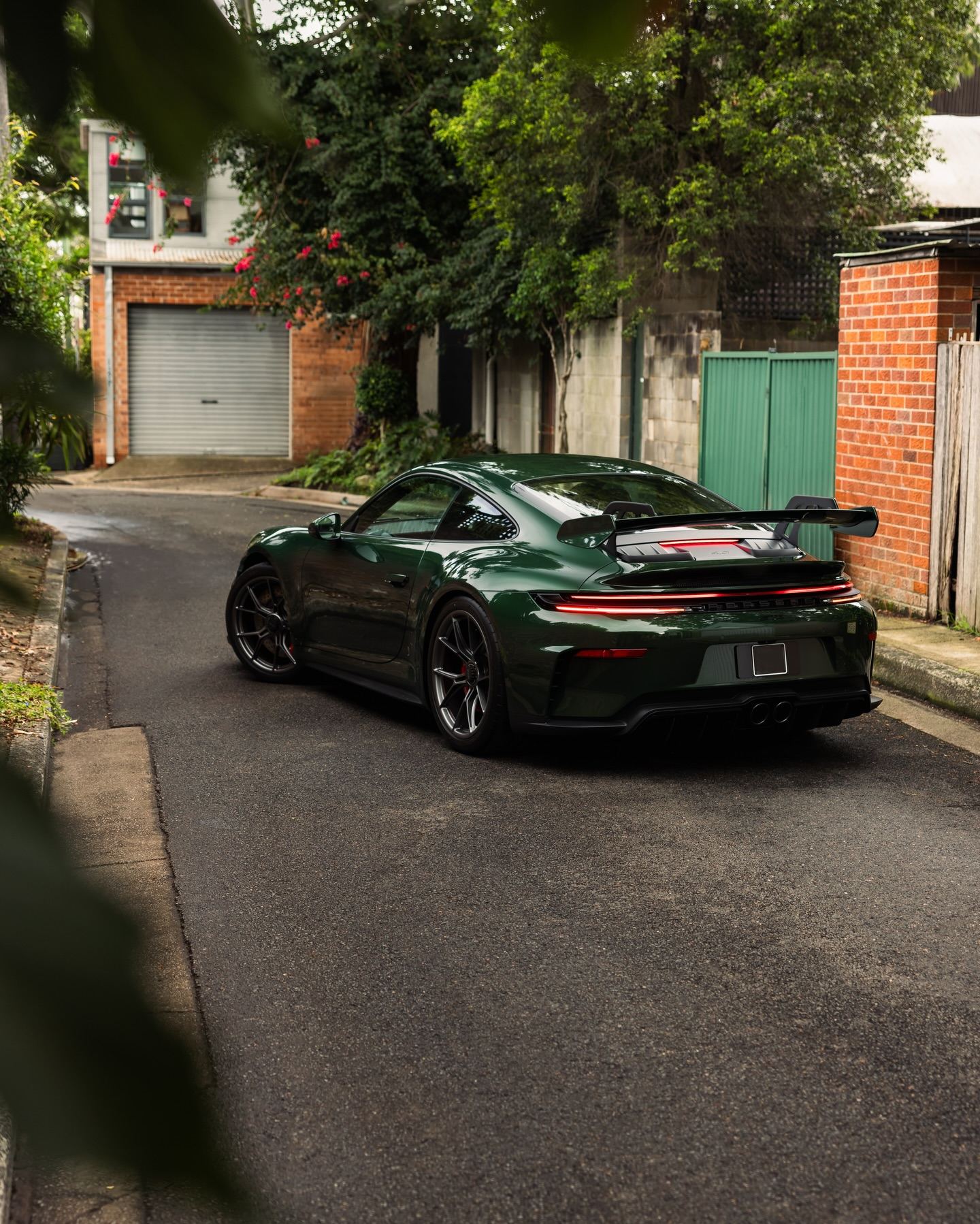 Dark green Porsche 911 GT3 from the rear three-quarter in a back lane