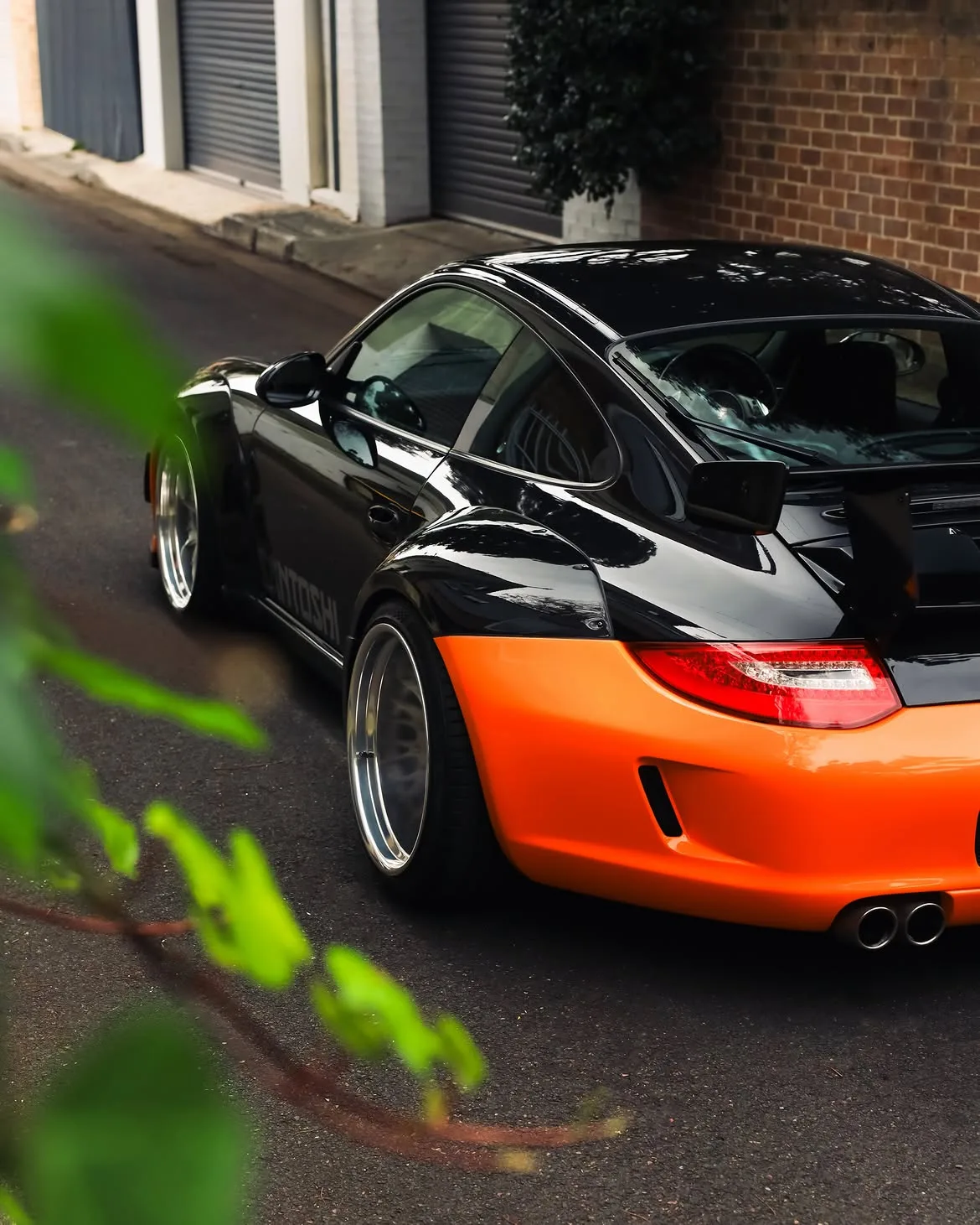 Black RWB widebody Porsche 911 with orange vinyl bumpers, by Roadbloc