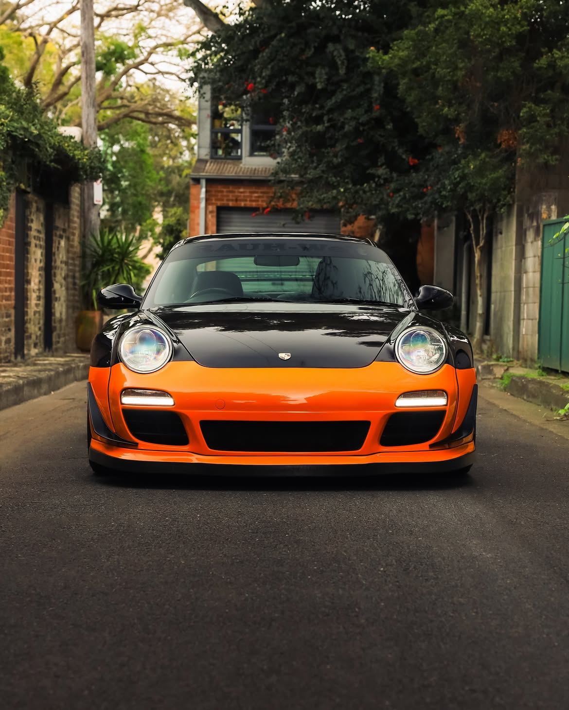 Black RWB widebody Porsche 911 with orange vinyl bumpers, by Roadbloc