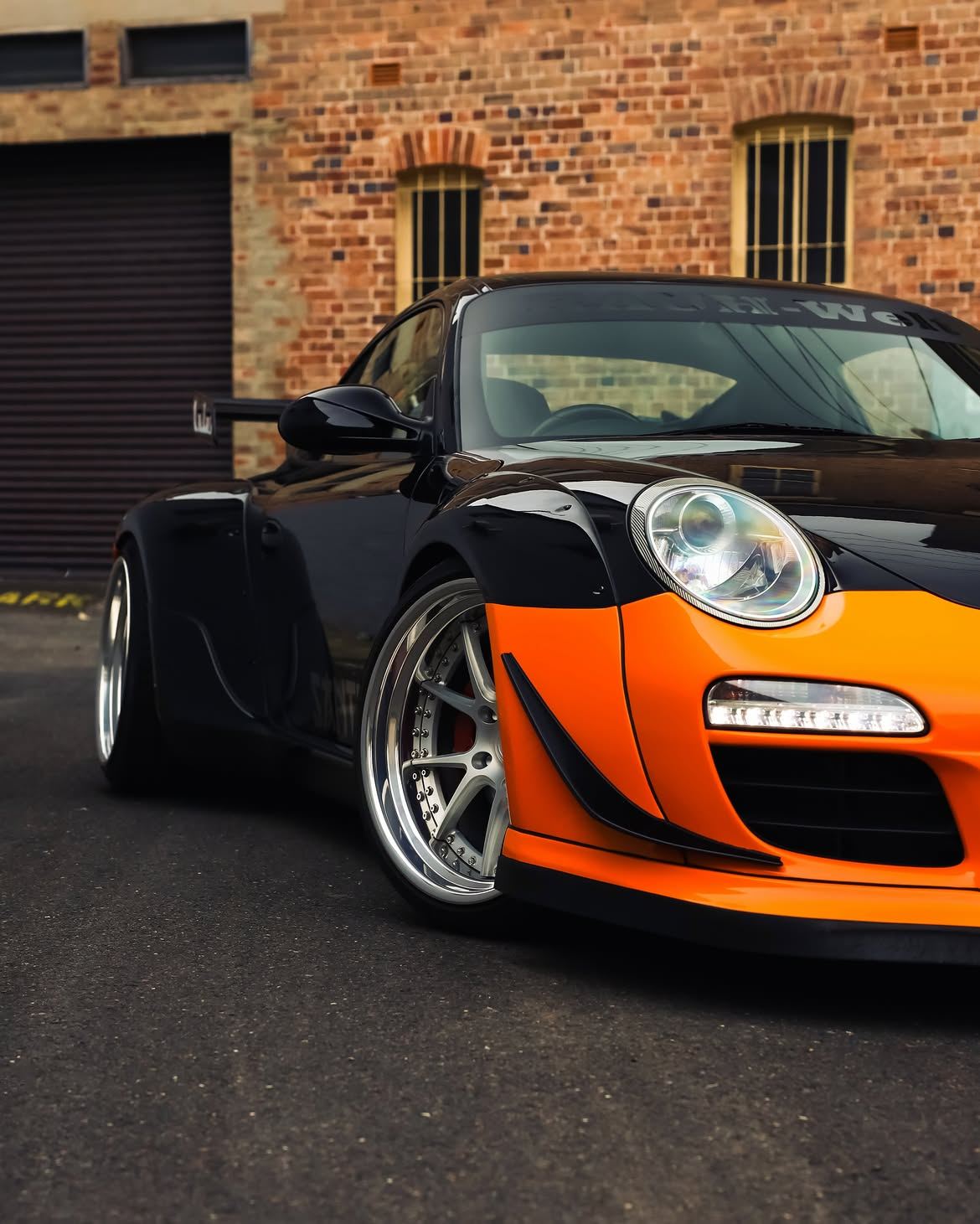Black RWB widebody Porsche 911 with orange vinyl bumpers, by Roadbloc