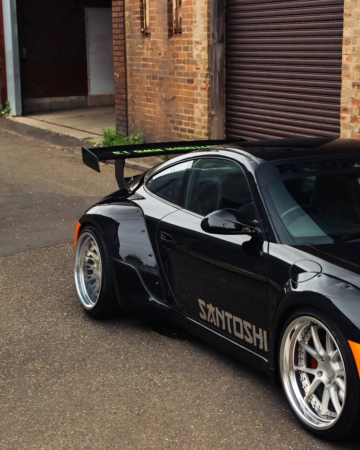 Black RWB widebody Porsche 911 with orange vinyl bumpers, by Roadbloc