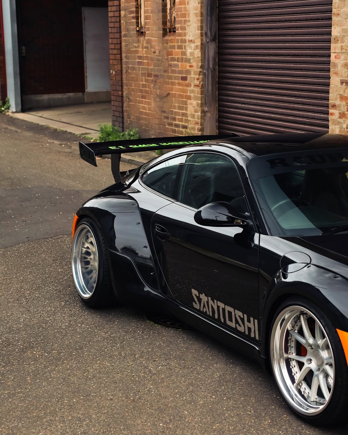 Black RWB widebody Porsche 911 with orange vinyl bumpers, by Roadbloc