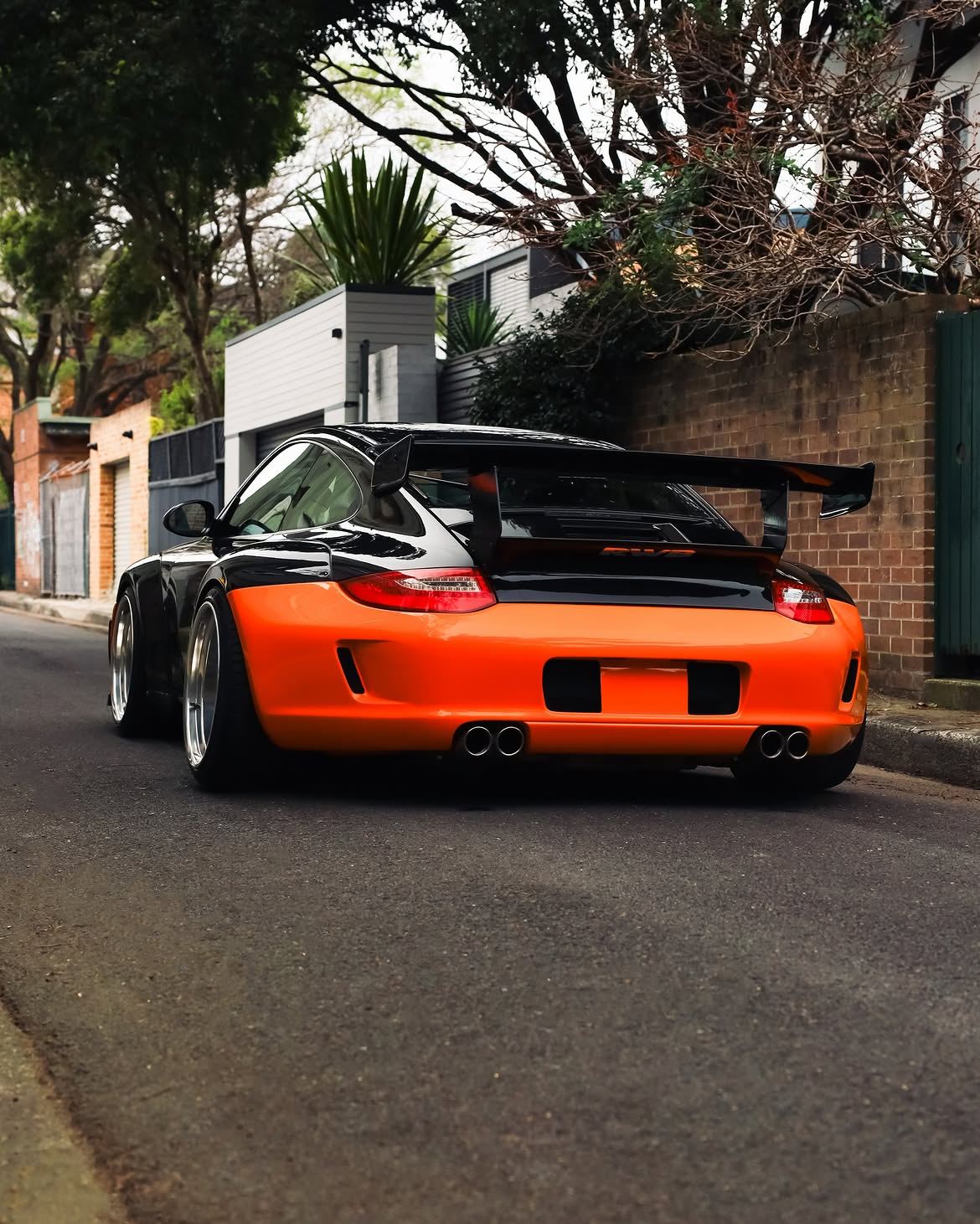 Black RWB widebody Porsche 911 with orange vinyl bumpers, by Roadbloc