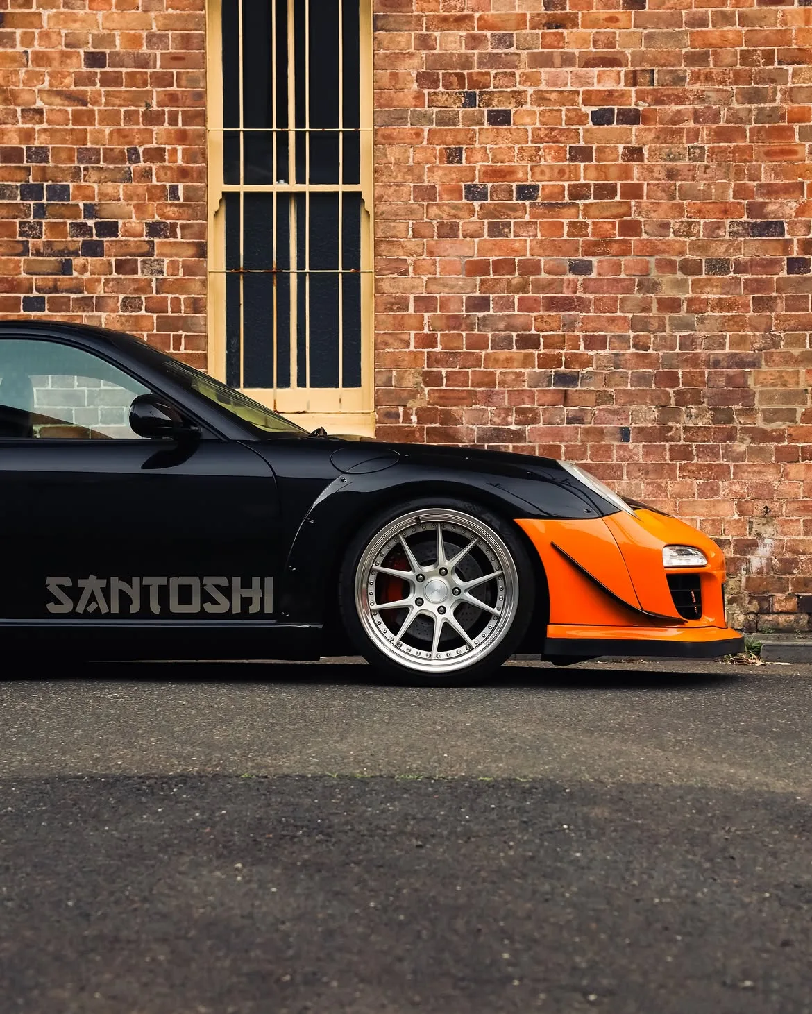 Black RWB widebody Porsche 911 with orange vinyl bumpers, by Roadbloc