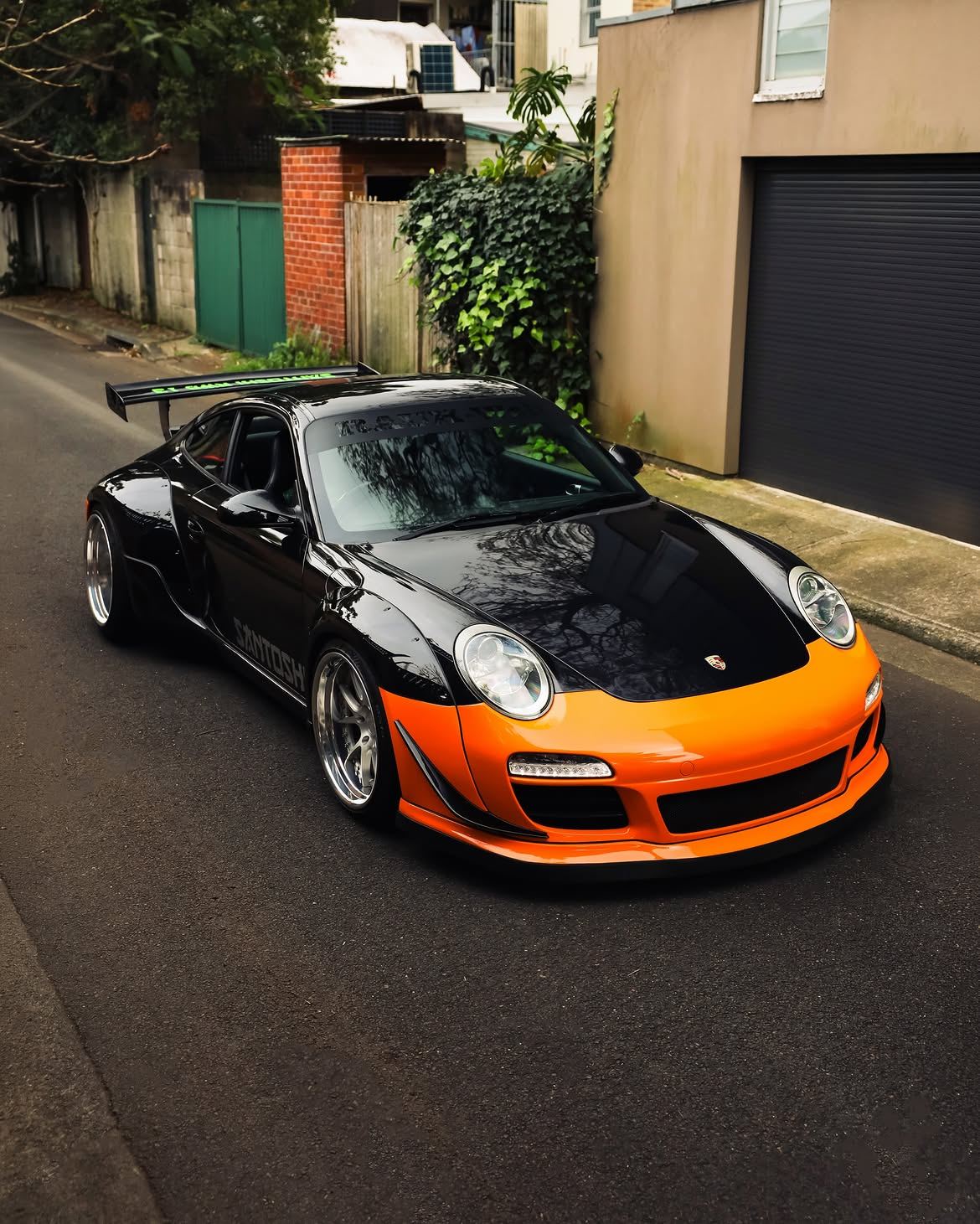 Black RWB widebody Porsche 911 with orange vinyl bumpers, by Roadbloc