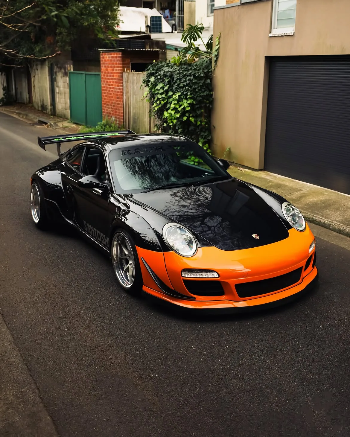 Black RWB widebody Porsche 911 with orange vinyl bumpers, by Roadbloc