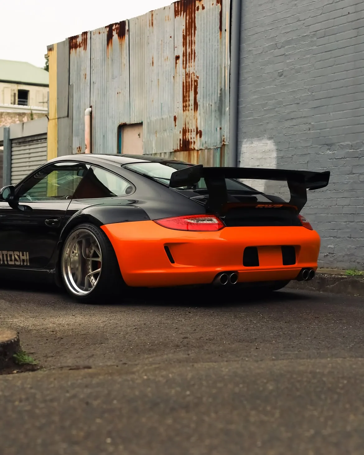 Black RWB widebody Porsche 911 with orange vinyl bumpers, by Roadbloc