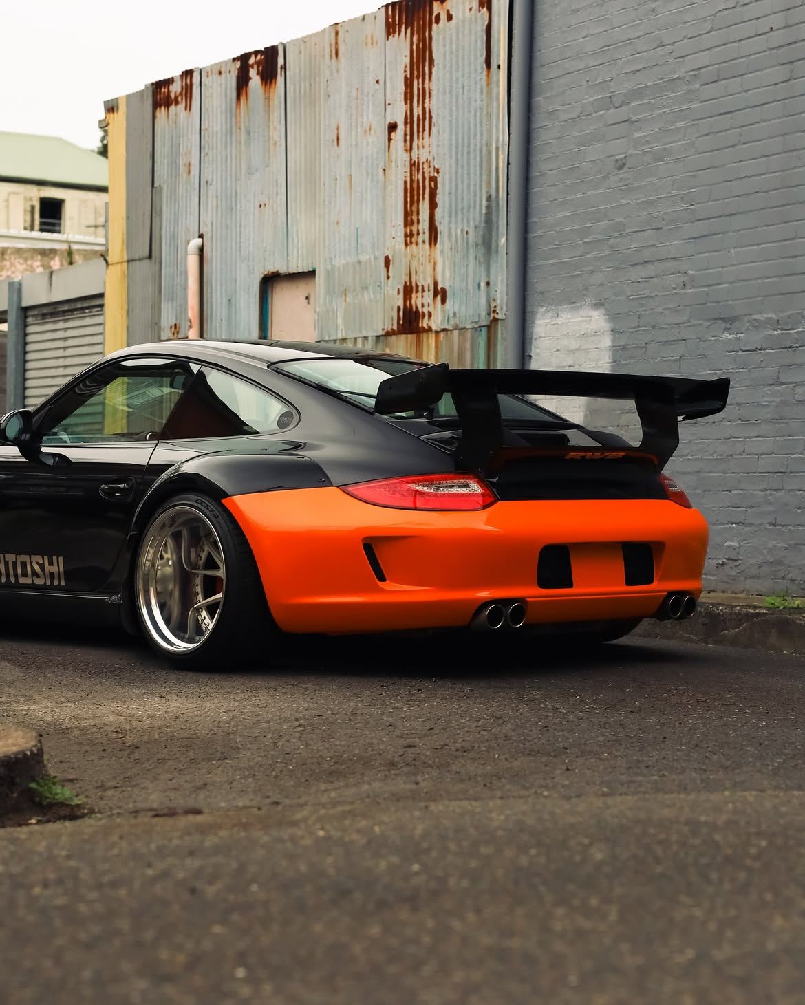 Black RWB widebody Porsche 911 with orange vinyl bumpers, by Roadbloc