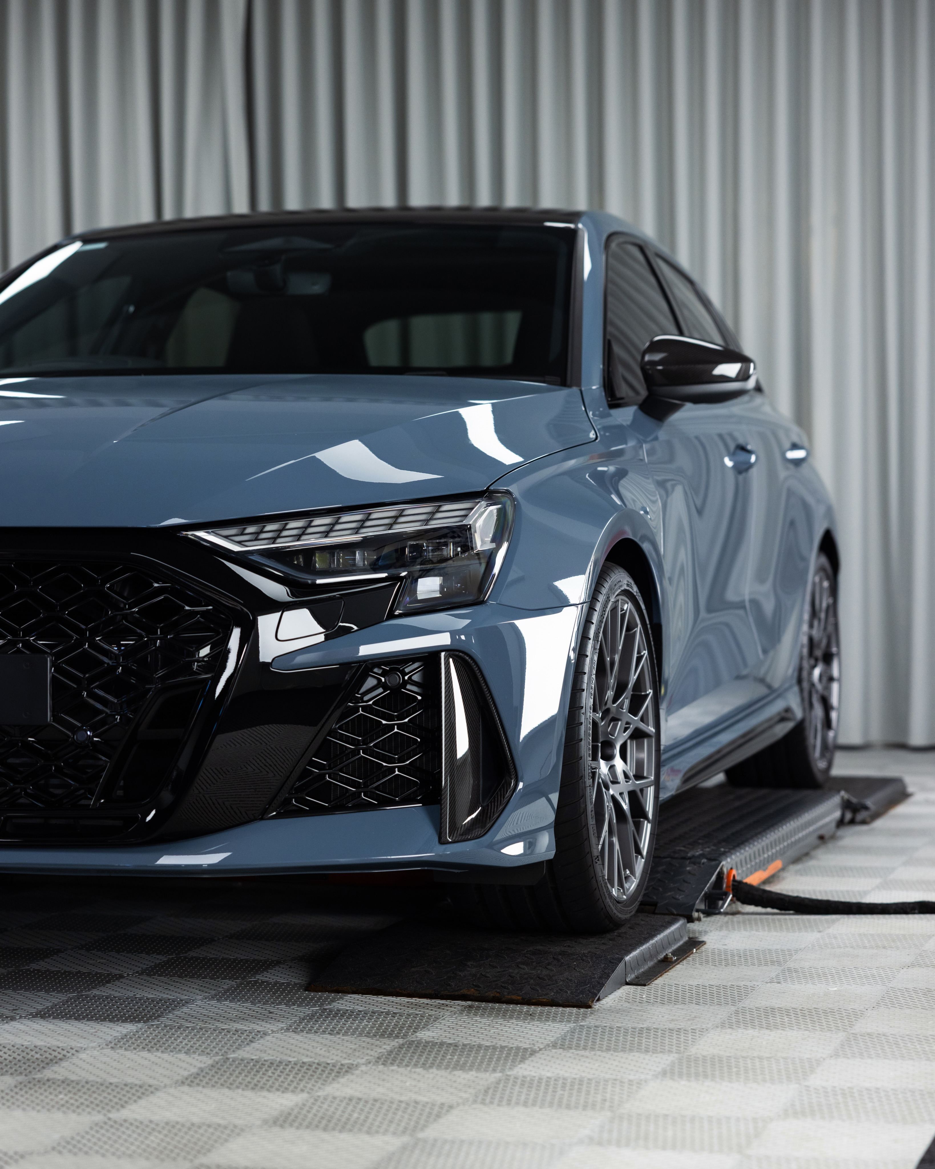 Grey Audi RS3 from a low front three-quarter angle in the studio
