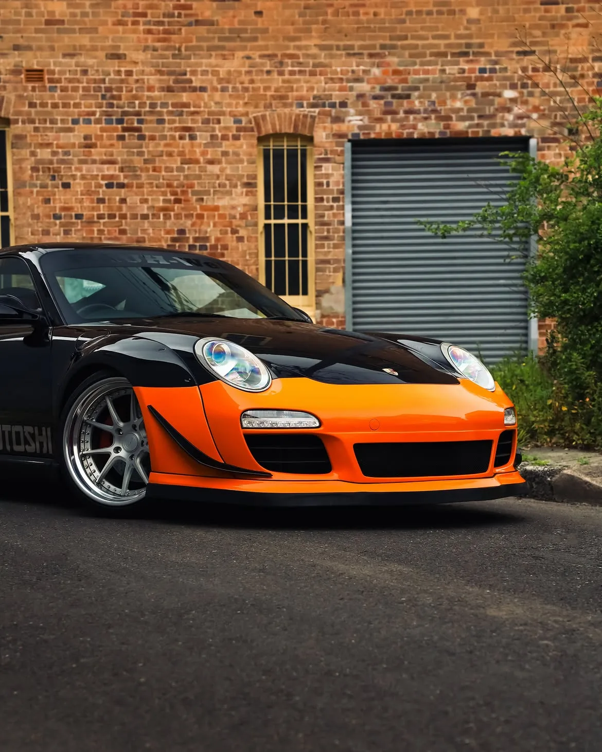 Black RWB widebody Porsche 911 with orange vinyl bumpers, by Roadbloc
