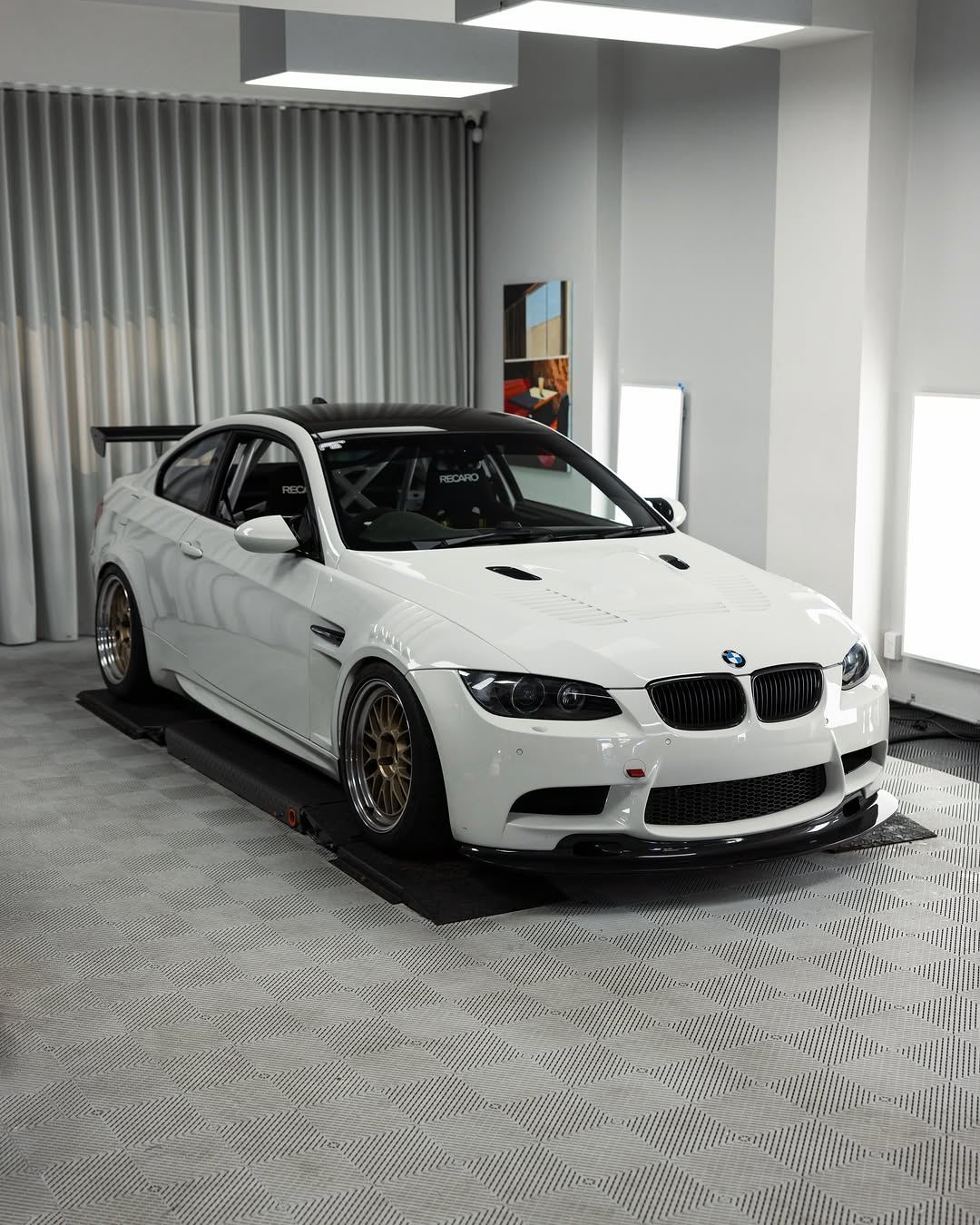 White BMW E92 M3 with gold wheels in the studio, front three-quarter view