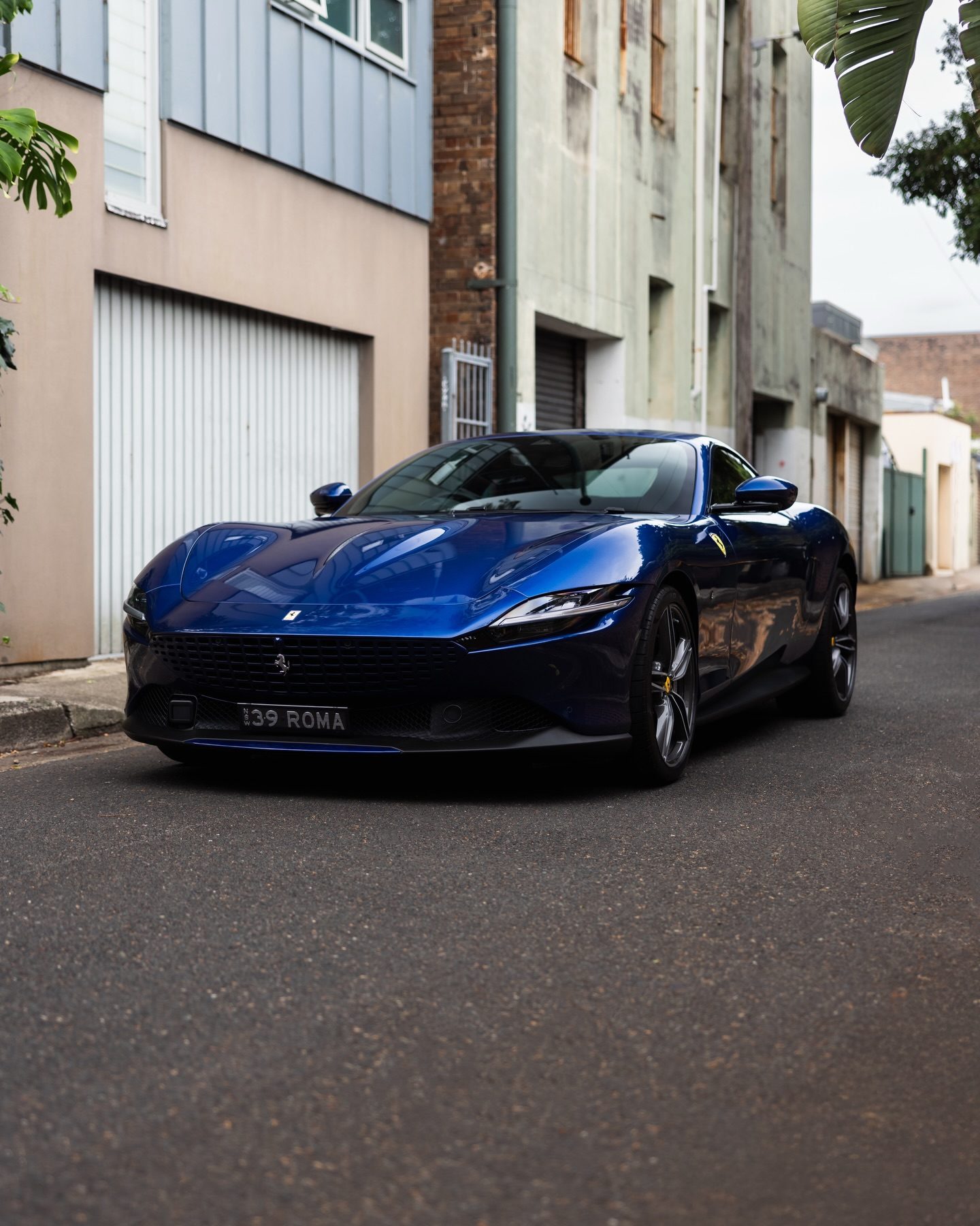 Deep blue Ferrari Roma from the front three-quarter in a Sydney lane